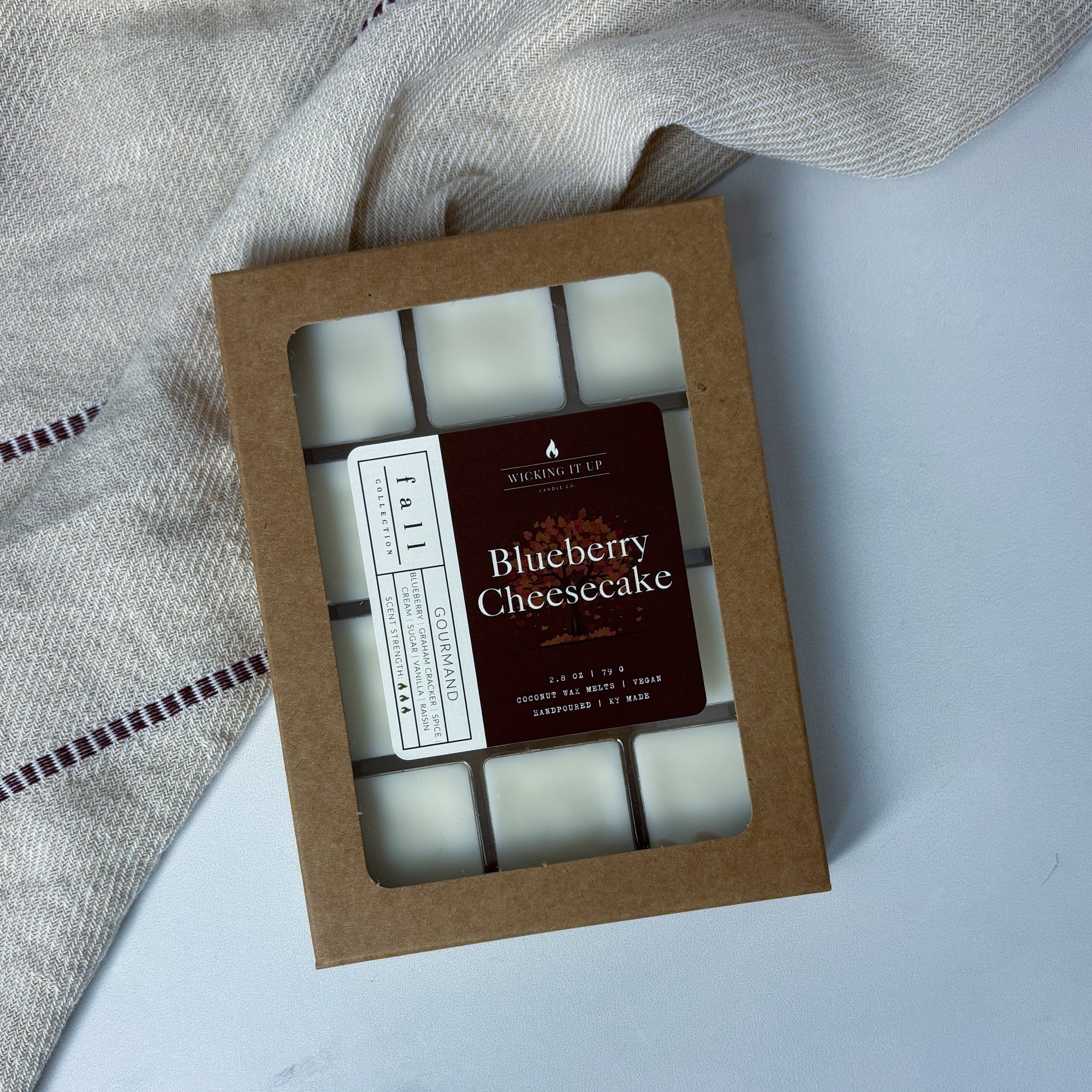 Box of Blueberry Cheesecake wax melts on a light background with a textured fabric.