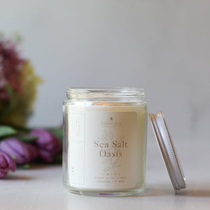 Candle labeled 'Sea Salt Oasis' with a blurred bouquet of flowers in the background