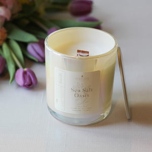 Candle labeled 'Sea Salt Oasis' with a bouquet of flowers in the background