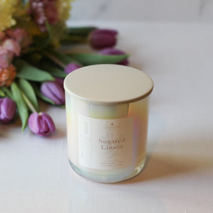 Candle labeled 'Sugared Limon' with a bouquet of flowers in the background