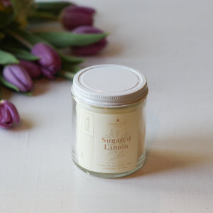 Jar of 'Sugared Limon' candle with purple tulips in the background