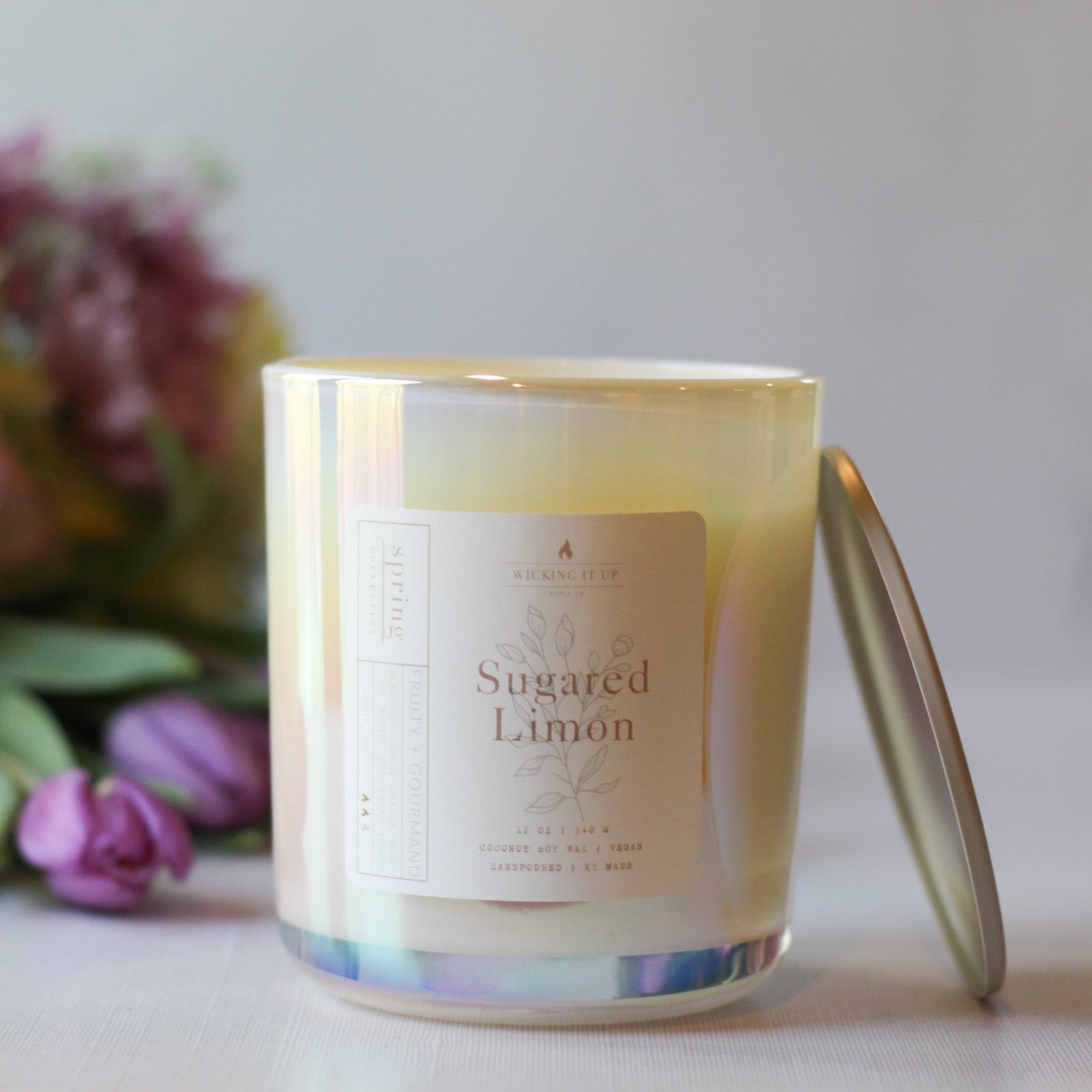 Candle labeled 'Sugared Limon' with a bouquet of flowers in the background